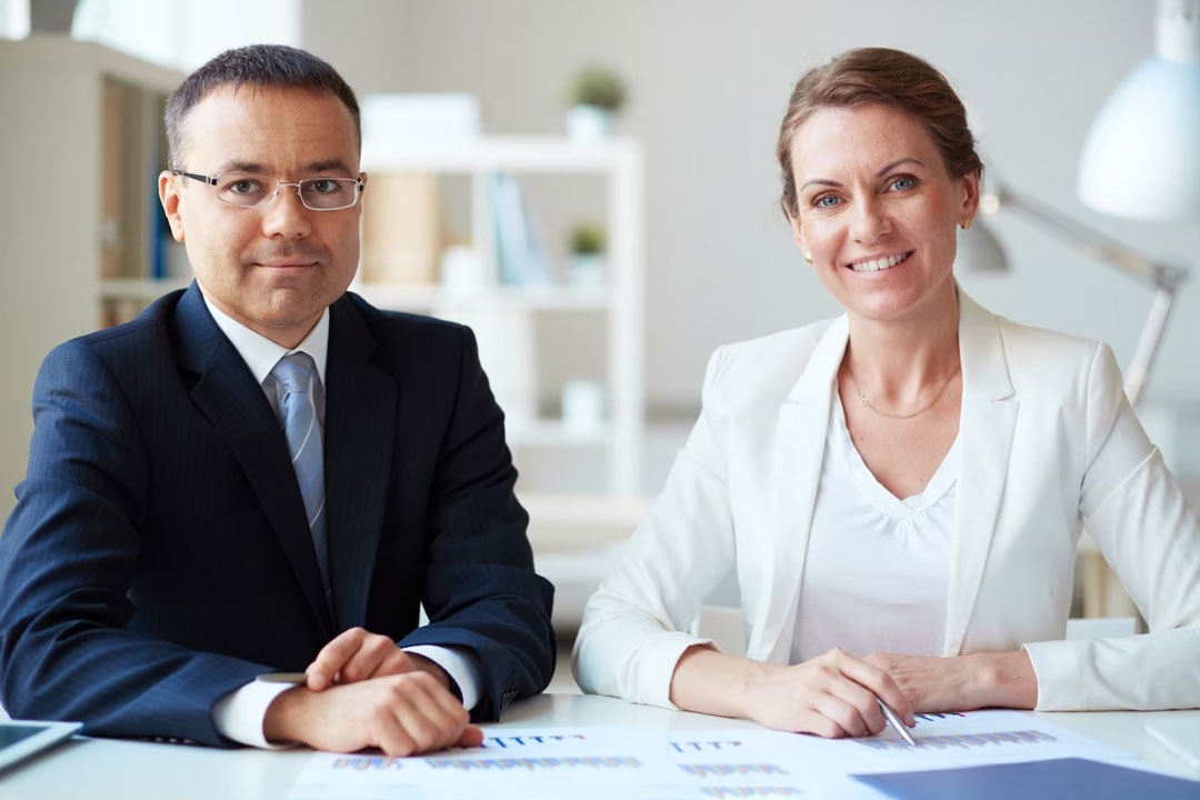 A couple of middle-aged executives, a man and a woman, analyzing the office's accounting data.
