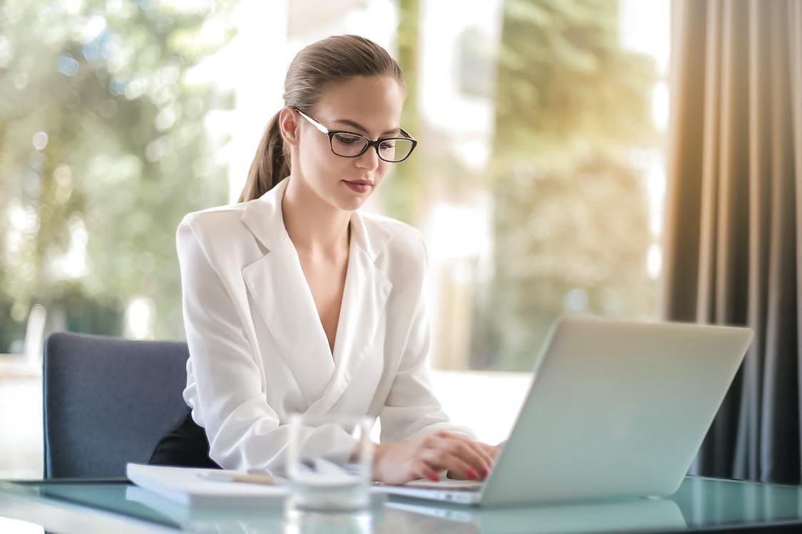 A young blonde woman working at her office desk.