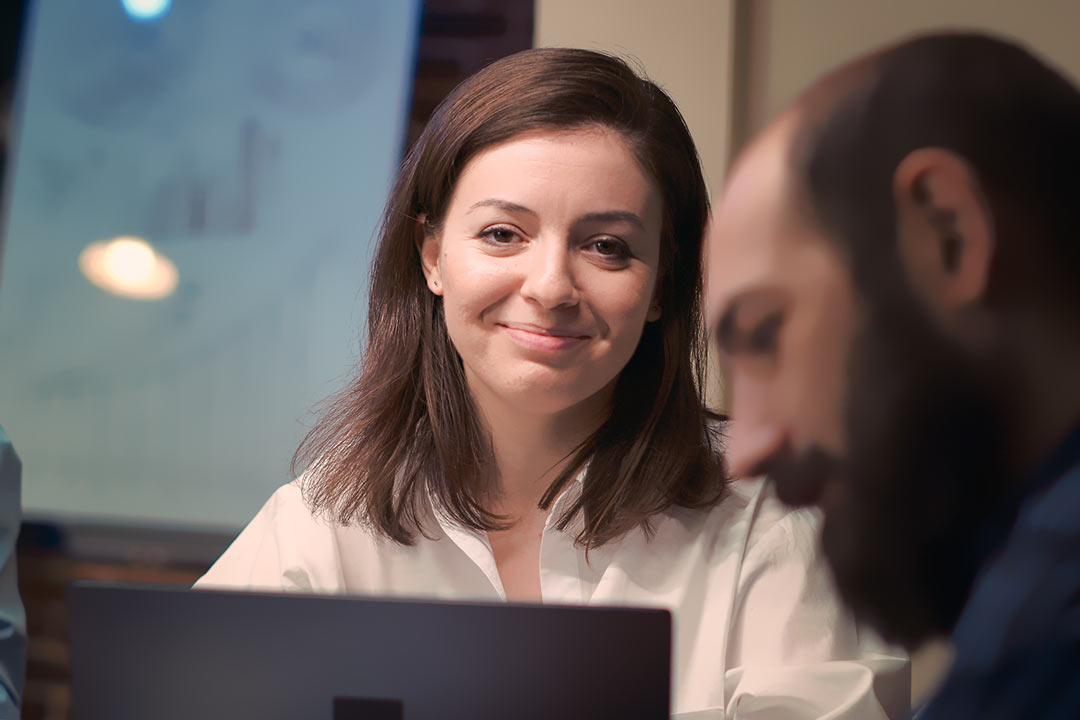 Empresária sorrindo de forma sutil em frente a um notebook
