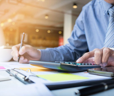 Executive using calculator and writing down data at accounting office desk