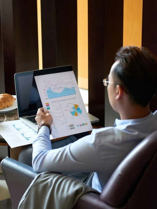 Executive with his back to a laptop, analyzing the company's accounting charts