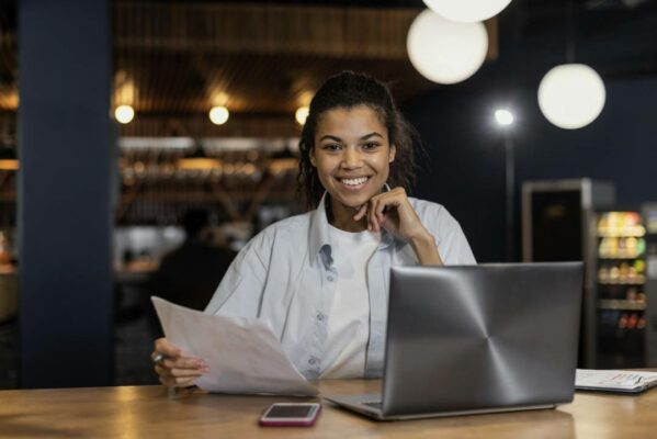 vista-frontal-da-mulher-sorridente-trabalhando-no-escritorio-em-frente-ao-laptop