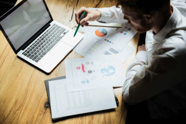 vista superior-jovem-empresário-de-sucesso-camisa-branca-mesa-de-trabalho-de-madeira